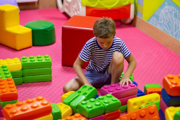 Cute boy playing with building toy colorful blocks. Preschool activities and early childhood education. Kid with happy face playing with plastic bricks. Plastic Large Toy. big cubes bricks